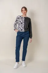 Buzo de manga larga con cuello redondo, combinado en dos tonos: negro liso en la mitad derecha y estampado animal print blanco y negro en la mitad izquierda.