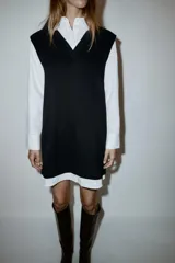 Vestido corto que combina una camisa blanca de manga larga con cuello solapa y botones frontales, con un chaleco de tejido negro de punto con escote en V.
