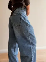 Pantalón de jean estilo palazzo en tono celeste medio, con corte amplio y recto. Presenta detalles de roturas sutiles en los bolsillos y ruedo, con cierre frontal y bolsillos laterales.