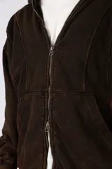 Campera oversize con capucha y cierre frontal, confeccionada en tela con acabado acid wash que le otorga un aspecto desgastado. Presenta costuras curvas decorativas en el frente y la espalda, puños y ruedo acanalados, y un calce relajado.
