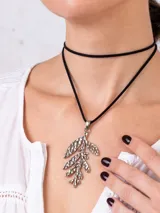 Collar tipo tiento de cuero gamuzado negro con dije colgante de acero en forma de rama con hojas texturizadas.