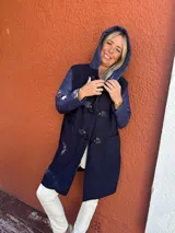 Montgomery de corte largo con capucha, confeccionado en una combinación de tejido de textura tipo bouclé en el cuerpo y mangas de nylon acolchado al tono. Presenta cierre frontal con botones tipo toggles y bolsillos laterales amplios.