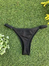 Conjunto de bikini negro con corpiño triangular fijo y bombacha colaless con argollas doradas en los laterales.