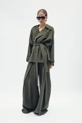 Chaqueta fluida de Zara, con cuello solapa, manga larga ajustable con trabilla y botón, y cinturón del mismo tejido con lazada. Presenta un diseño de corte recto y forro interior a tono.