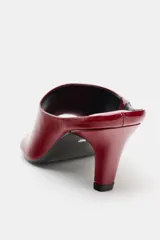 Sandalia tipo mule de mujer, color rojo vino, con acabado en charol brillante. Presenta una capellada ancha que cubre parte del empeine y un tacón fino y curvo.