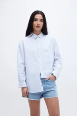Camisa celeste a rayas verticales blancas, de algodón, con cuello solapa clásico, bolsillo cuadrado en el pecho, botones personalizados y calce relaxed.