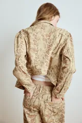 Cazadora de cuello solapa y manga larga con estampado animal print de serpiente, bolsillos con solapa en el pecho y cierre frontal con botones metálicos.