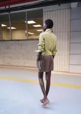 Chaqueta corta de piel de ante color verde, con diseño recto, cuello camisero, manga larga, dos bolsillos de parche en la parte delantera y cierre frontal con botones.