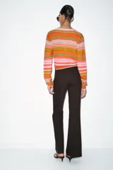 Chaqueta de punto con cuello pico y manga larga, con cierre frontal de botones. Presenta un estampado de rayas horizontales en tonos rosado, naranja y verde.