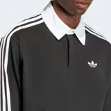 Camiseta de manga larga estilo rugby Adidas Originals, color negro con cuello polo blanco y las icónicas tres rayas blancas en las mangas. Presenta el logo del trébol bordado en el pecho y un corte holgado.