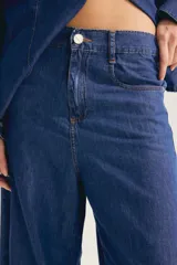 Jean de denim celeste claro, de tiro alto y pierna ancha, con bolsillos frontales y traseros, y cierre de botón y cremallera.