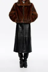 Chaqueta corta de corte globo confeccionada en pelo sintético color marrón, con cierre frontal de cremallera metálica y cuello camisero amplio. Presenta manga larga recta y bolsillos laterales de vivo.