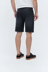 Bermuda de denim de corte relaxed fit, tiro medio y color negro con efecto deslavado. Cuenta con bolsillos clásicos y cierre frontal con botón y cremallera.