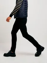 Pantalón de jean corte skinny, color azul medio, con diseño de cinco bolsillos y cierre frontal con botón y cremallera.