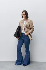 Jean flare de tiro alto, color azul, con calce ajustado en cadera y muslos, y ruedo desflecado.