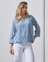 Blusa celeste de lyocell con cuello a la base y escote en V con lazo de ajuste. Manga larga amplia.