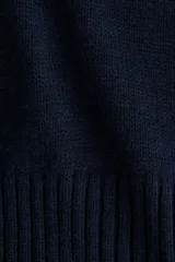 Buzo de punto fino en color azul marino, con cuello alto acanalado, mangas tres cuartos y hombros caídos. Presenta terminaciones acanaladas en puños y ruedo.