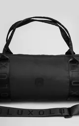 Bolso cilíndrico porta yoga-mat color negro, confeccionado en cordura de alta densidad. Cuenta con correas regulables grabadas con el logo de la marca, manijas cortas para agarre manual, compartimento principal con cierre metálico reforzado y un bolsillo trasero pequeño con cierre para objetos de valor.