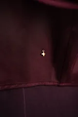 Camisa de satén bordó con cuello clásico, mangas largas con puños abotonados y cierre frontal con botones.