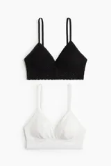 Pack de dos soutiens de encaje, uno negro y otro blanco, con breteles ajustables y copas acolchadas con relleno extraíble. Sin cierre ni aros.