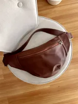 Riñonera de cuero marrón con correa ajustable y cierre superior con cremallera. Herrajes color bronce.