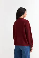 Sweater de punto color bordó con diseño de ochos, cuello redondo y mangas largas con puños acanalados.