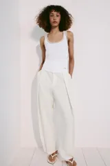 Musculosa de algodón color blanco con cuello redondo amplio y sisas. Cuenta con detalles de ribetes dorados brillantes en el escote, tirantes y costuras laterales.