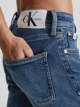 Jeans de mezclilla elástica de algodón, color azul medio con efecto desgastado y lavado. Presentan un corte skinny fit, cintura de talle bajo, bragueta con cremallera y estilo de 5 bolsillos.