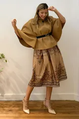 Capa corta negra de paño italiano con cuello alto y cinturón con hebilla dorada.