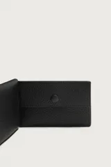 Tarjetero plegable de piel vacuna color negro, con diseño texturizado, cuatro ranuras para tarjetas y monedero con cierre de broche a presión.