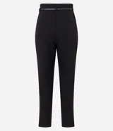 Pantalón carrot negro de sastrería, con bolsillos, pliegues y cinturón fino de cuero sintético.