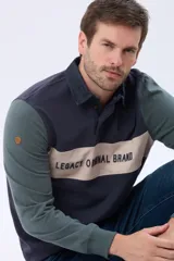 Remera tipo polo de manga larga con diseño color block en azul marino, verde y una franja central en beige con el texto Legacy Original Brand estampado. Presenta cuello camisero con cierre de botones y puños acanalados.