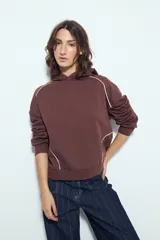 Canguro de silueta amplia color bordó, con capucha y detalles de líneas blancas que recorren el frente y las mangas.