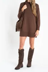 Vestido corto de punto color marrón, con cuello alto, mangas largas con puños acanalados y ruedo acanalado. Presenta un diseño de corte recto y holgado.