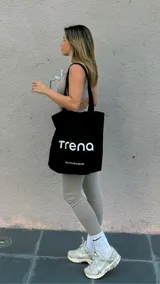 Bolso tote negro de brin de algodón con asas largas y estampado frontal con el logo de la marca en blanco.