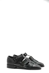 Zapato tipo cangrejera de cuero color marrón, con diseño de tiras entrelazadas, punta cerrada y pulsera con hebilla ajustable al tobillo. Cuenta con un taco bajo de madera.