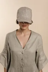 Gorra con visera confeccionada en lana fina sin teñir, con un sutil patrón de tejido en espiga.