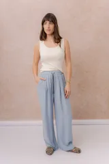 Pantalón celeste de corte amplio y fluido, confeccionado en tela liviana con cintura elastizada y cordón de ajuste en contraste. Cuenta con bolsillos laterales y pierna recta.