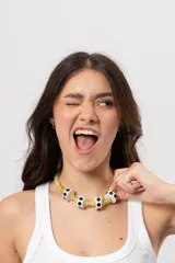 Collar corto de cuentas de piedra en tonos amarillos y verdes, intercaladas con cuentas cilíndricas blancas con lunares negros.