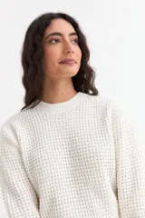 Sweater de punto con textura tipo waffle, color blanco, de corte clásico con cuello redondo y mangas largas.