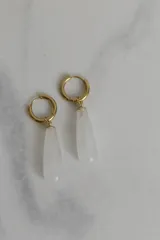 Aros tipo argolla de acero quirúrgico dorado con dije colgante en forma de gota de piedra natural blanca.