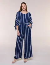 Enterito largo de crepe color azul marino con diseño de rayas verticales blancas. Cuenta con escote redondo, mangas tres cuartos con detalles de lazos en los puños, cintura elastizada con lazo extraíble para ajustar, bolsillos laterales y pantalón de corte amplio.
