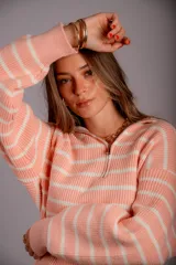 Buzo de punto color beige con rayas horizontales blancas, cuello polo con cierre de cremallera y mangas largas.