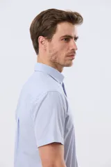 Camisa de manga corta a rayas celestes y blancas, con cuello abotonado, bolsillo frontal con logo bordado y cierre frontal de botones.