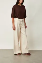Jean azul oscuro de corte wide leg y tiro alto, con costuras pespunteadas verticales al frente y cinturón incorporado con hebilla cuadrada.