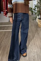 Pantalón de jean azul oscuro con corte wide leg, tiro alto y costuras verticales decorativas en el frente. Presenta un ruedo desflecado y un diseño de pierna ancha.
