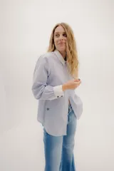 Camisa de manga larga color rosa claro con textura, cuello y puños blancos contrastantes. Los puños tienen tres botones rosados.