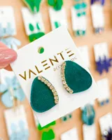 Par de aros colgantes de acrílico verde esmeralda con forma irregular y detalle de strass dorados en el borde superior.