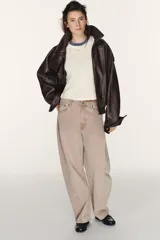 Jeans de tiro medio, color beige rosado con efecto lavado, corte amplio (baggy balloon) y detalle de costuras torcidas en el frente de las piernas.