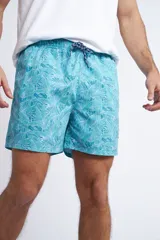 Short de baño con cintura elástica y cordón ajustable, confeccionado en tela ligera de secado rápido. Presenta un estampado botánico integral en tonos amarillos, blancos y azules, con dos bolsillos delanteros y uno posterior.